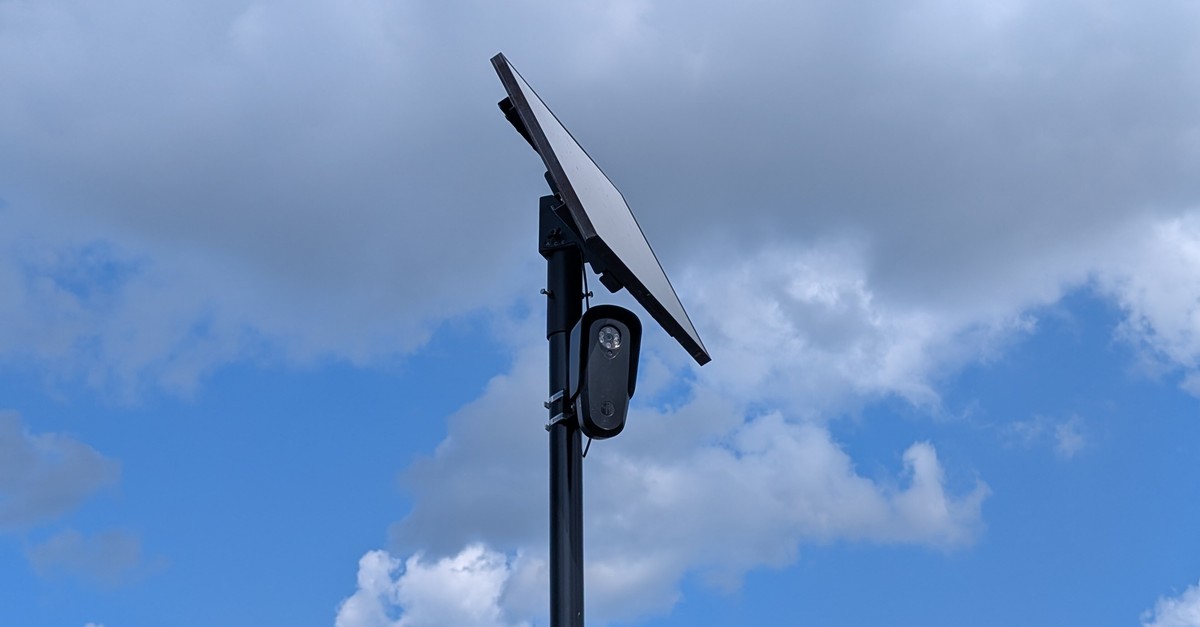 A Flock Safety license plate reader camera with solar panel mounted on a pole in a parking lot in Eatontown, New Jersey. Photo by MiracleMiles via Wikimedia Commons, CC BY 4.0.