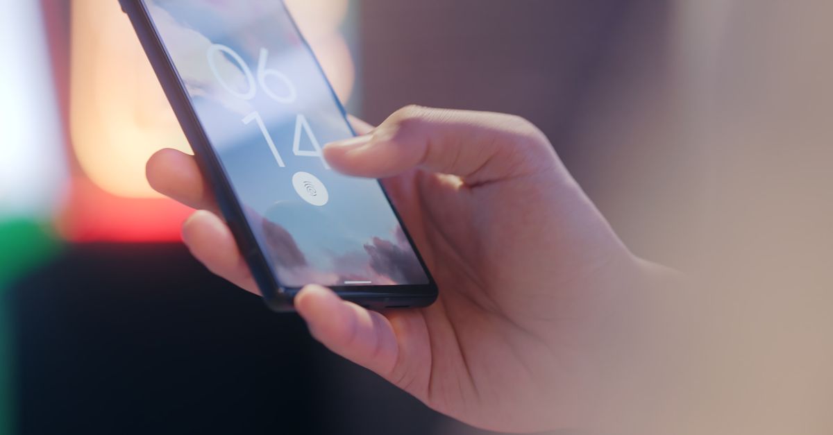 A hand holding a smartphone being unlocked with a fingerprint