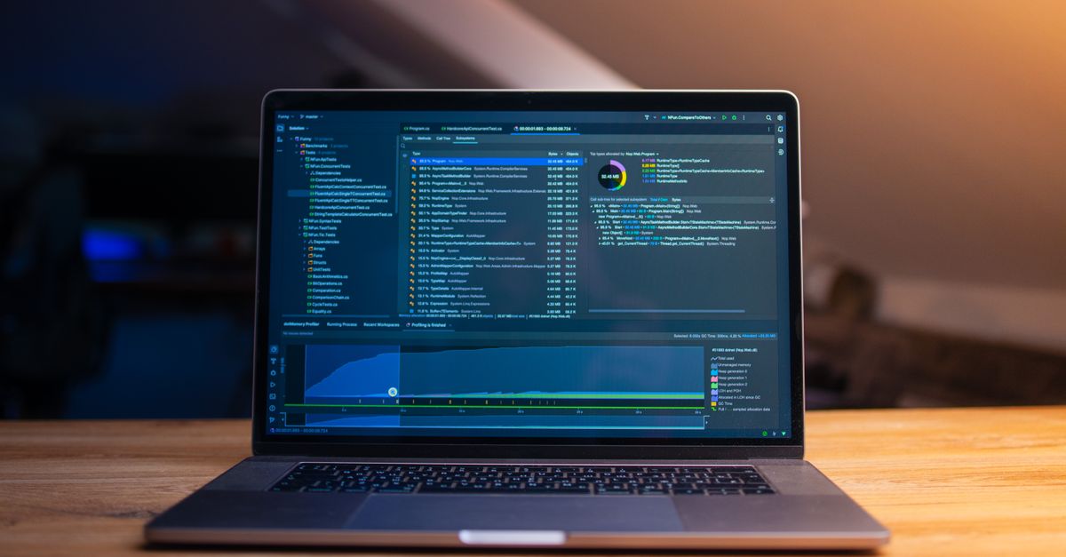 A laptop on a desk with code on the screen in a quiet, dimly lit workspace